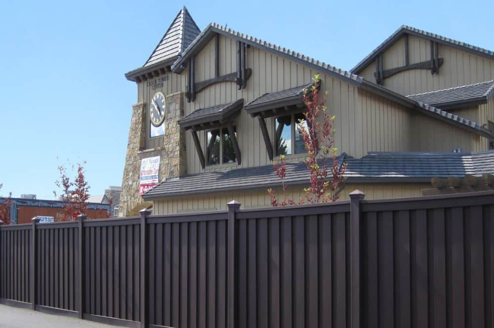 A newly installed brown composite fence demonstrates the benefits of having a noise-reducing fence for your business or home.